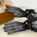 Detail view of black fishnet lace gloves featuring elegant satin bows and faux pearls. - Big Bow White / Black
