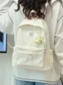 Detail shot of the striped canvas backpack featuring front pocket and cute pendant design. - With Pendant / Yellow