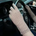 Close-up detail of women's beige floral lace UV protection driving gloves in summer car view. - One Size / Coffee