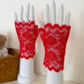 Dettaglio ravvicinato di guanti in pizzo rosso senza dita con delicato motivo floreale, elegante. - Taglia unica / Rosa / Rosso