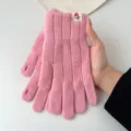 Close-up detail of pink knitted winter gloves with ribbed cuff and cute floral label. - One Size / Pink