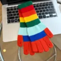 Detailed view of colorful rainbow striped fingerless knit gloves for women winter warmth. - One Size / Orange