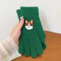 Green knit winter glove detail with cute felt corgi cartoon animal decoration close-up - Green