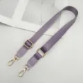 Detailopname van de paarse nylon tasriem voorzien van glanzende gouden metalen accessoires. - Lichtpaars