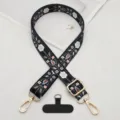 Close-up of bohemian style embroidered phone strap details with durable metal hardware and black tether tab. - Black and White Floral with T-Gasket
