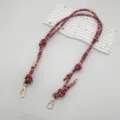 Detailed view of colorful woven bag strap accessory with metal clasps on a white wavy prop. - Silver Hook / Purple