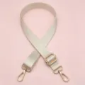 Gedetailleerde opname van de beige nylon tasriem met gouden metalen gesp accessoires. - Broken Wit
