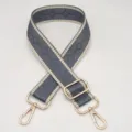 Vista detallada de la correa de bolso tejida en gris con bordes beige y herrajes dorados. - Gris Oscuro Con Bordes Beige
