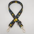 Primer plano de una correa de bolso negra de 2.5 cm con estampado floral étnico y ganchos. - Gancho Dorado / Flor Negra y Amarilla