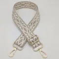 Vista dettagliata della larga tracolla per borsa intrecciata con motivo geometrico e dorata. - Beige Cachi Bianco