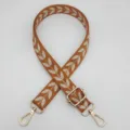 Detailopname van oranje geweven tasriem met gouden hardware en geborduurd bladmotief. - Zilveren Haak / Bruin Beige