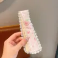 Primo piano del cerchietto in pizzo floreale con fragola e grazioso fiocco decorativo. - Fragola con Fiocco Rosa