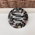 Primo piano dettagliato del creatore di crocchie in tessuto floreale nero con pettine. - Floreale Nero