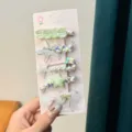 Children's marine theme hair clip set, detail shot showing starfish and shell designs on backing card. - Pearl Starfish 5-Piece Set / Green