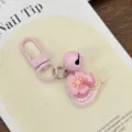 Close-up detail of the pink cherry blossom dessert bell keychain pendant for cute backpack. - Cake Slice