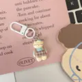Close-up detail of cute cartoon animal overall keychain pendant accessory on pink background. - Blue Plaid Cat
