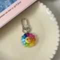 Detailed close-up of a colorful rainbow flower keychain with a playful expression and clasp. - Seven-Color Flower (Smirking)