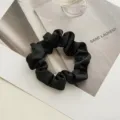 Elegante scrunchie per capelli in raso nero, consistenza liscia per lo styling, minimal. - Nero