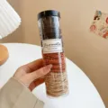 Colorful elastic hair ties in a clear cylinder container, perfect for daily hairstyles. - Black Orange 3-Color 200 Pcs