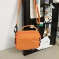 Detailaufnahme der hellorangefarbenen Nylon Umhängetasche mit robustem Reißverschluss. - Orange