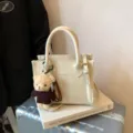 Schickes cremeweißes Umhängetasche Detail mit niedlichem Plüschbär-Anhänger und Henkel. - Weiß mit Anhänger