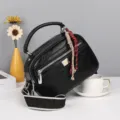 Schwarze Boston Handtasche aus Ölwachsleder mit breitem gemustertem Gurt und Metalldetail. - Schwarz
