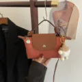 Kleine Nylon Umhängetasche im Dumpling-Stil, in Braun und Orange mit flauschigem Anhänger. - Hellbraun