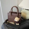 Braune Leder Umhängetasche für Damen, minimalistische Handtasche mit süßem Bärenanhänger. - Kaffee Mit Anhänger