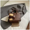 Elegante braune Damentasche aus Leder mit süßem Bärenanhänger und praktischem Umhängegurt. - Kaffeebraun