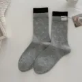 Graue Damensocken mit süßem Herzmuster, braunem Rippbündchen und Stoffetikett Detail. - Einheitsgröße / Hellgrau