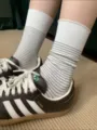 Dettaglio di calze a righe retrò abbinate a scarpe casual, modello in cotone traspirante. - Taglia unica / Bianco