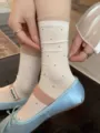 Detailed view of women mid-calf socks featuring cute black polka dots and sheer organza cuffs. - One Size / Milk White