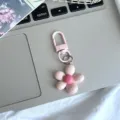 Primer plano detalle del bonito llavero de metal con forma de flor rosa de cinco pétalos. - Rosa