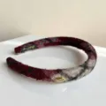Detailaufnahme des stilvollen roten Tweed-Haarreifs mit einem kleinen Metallschildchen. - Schwarz-Rot Kariertes Haarband