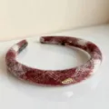 Detailansicht eines dicken roten Karo-Stoffhaarreifs mit einem goldenen Happy-Metallschild. - Glänzendes Rotes Haarband