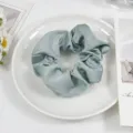 Detailed view of elegant light green satin scrunchie, smooth texture for hair styling and wear. - Elegant Blue