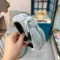 Vue détaillée d'un serre-tête plissé argenté avec nœud, montrant la texture du tissu large. - Gris