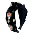 Close-up detail of black velvet Halloween crystal rhinestone and colorful sugar skull headband. - Black