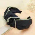 Black denim knotted headband with trendy metallic zipper trim, fashionable hair accessory. - Black