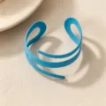 Close-up detail of a bright blue open cuff bracelet, minimalist geometric spiral design style. - Blue