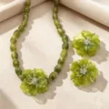 Green resin flower necklace and earrings set close-up view, elegant resort fashion jewelry details. - Green