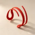 Close-up detail of the modern minimalist red curved cuff bracelet design, sleek and unique styling. - Red