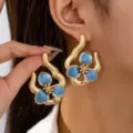 Detailed shot of irregular geometric blue enamel flower earrings, elegant gold design for women. - Teal