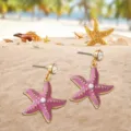 Chic pink starfish dangle earrings with sparkling crystals, perfect for summer beach vacations. - Violet
