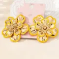 Close-up detail shot of exquisite gold flower earrings with yellow enamel edge design. - Yellow