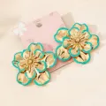 Close-up detail shot of Korean style gold floral earrings featuring chic turquoise edges. - Emerald
