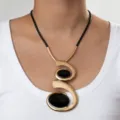 Detailed view of the oversized bohemian spiral pendant necklace with black oval stones. - Double Spiral Golden Necklace