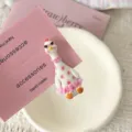 Close up of a cute quirky goose hair clip featuring sunglasses and pink polka dot dress. - Goose Shape / Polka Dot Goose