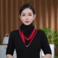 Close-up detail of the knit triangular scarf with red and black color block and gold chain pendant. - Black and Red