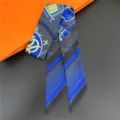 Detailed shot of a luxury silk twilly scarf featuring elegant carriage patterns and blue tones. - 24